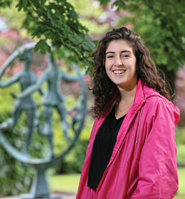 Eliana Padwa, a Brandeis student, stands in front of a sculpture on campus